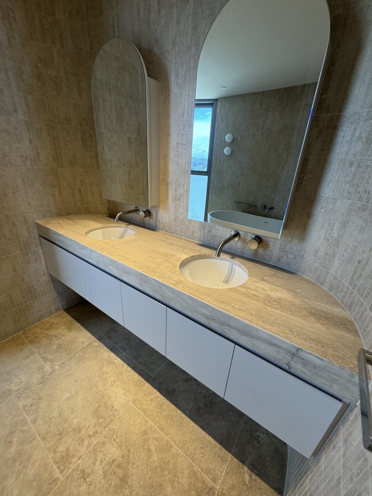 Travertine double vanity with twin arched mirrors and brushed tapware in a Gold Coast bathroom renovation