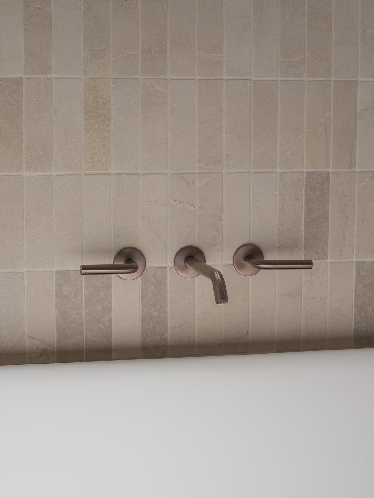 Brushed bronze wall mixers and spout on stack-bond stone tiling in a Gold Coast bathroom renovation
