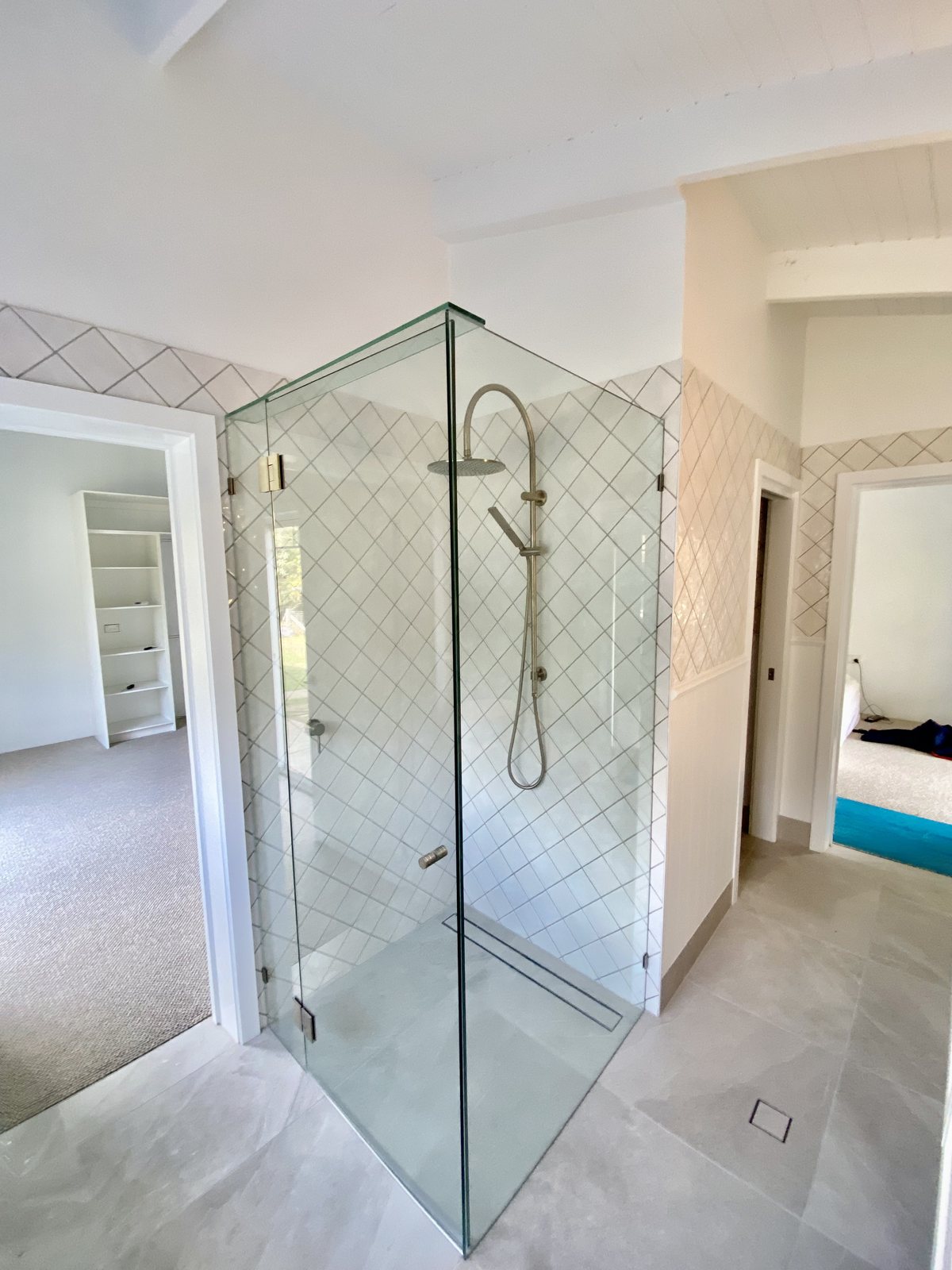 A frameless glass shower screen and tiled shower in a Gold Coast bathroom — the sealant, grout, screen edges and floor waste are the first things checked in a unit wet-area inspection