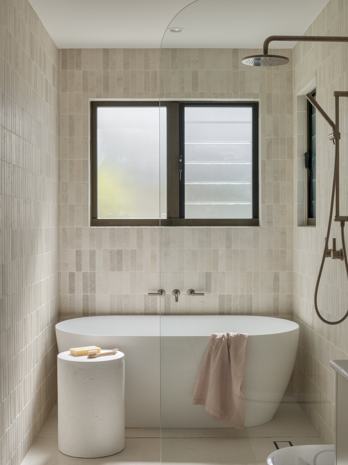 Freestanding oval bath beside a window with a rail shower in a Gold Coast bathroom renovation