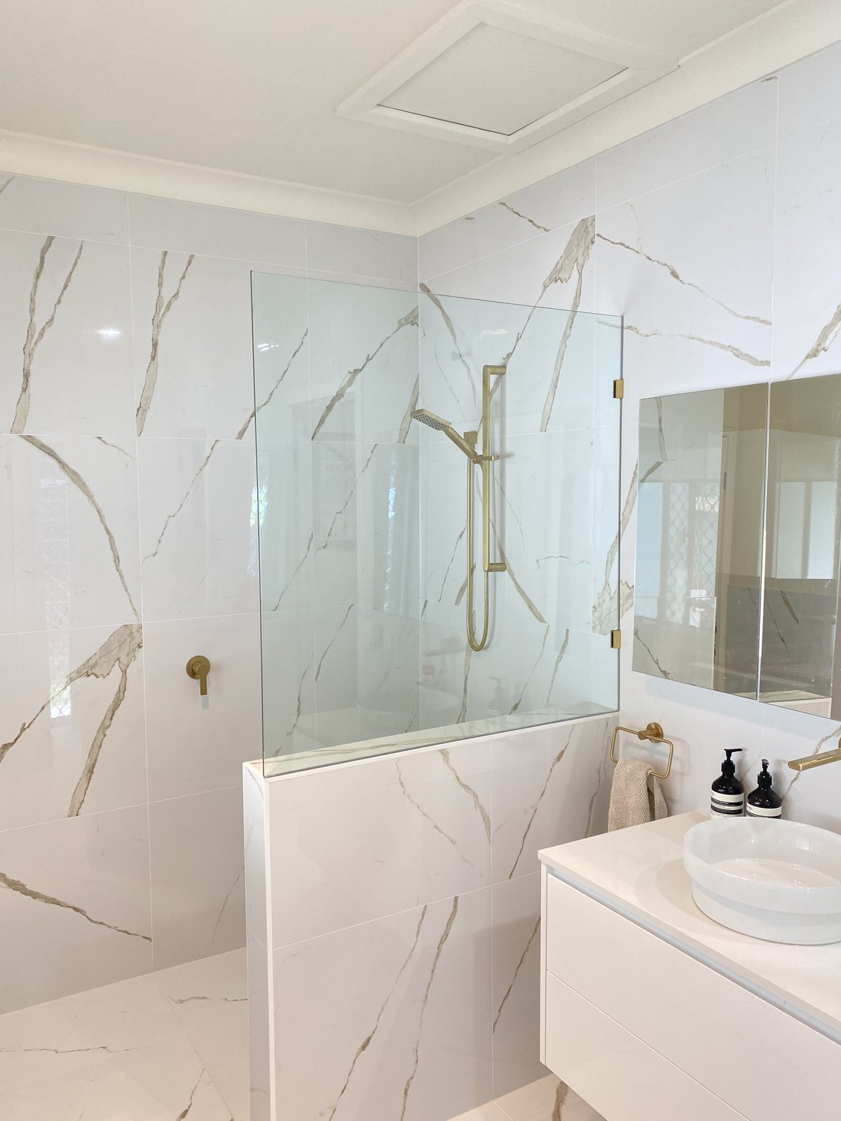 Marble-look bathroom renovation with a walk-in shower and brushed brass tapware on the Gold Coast