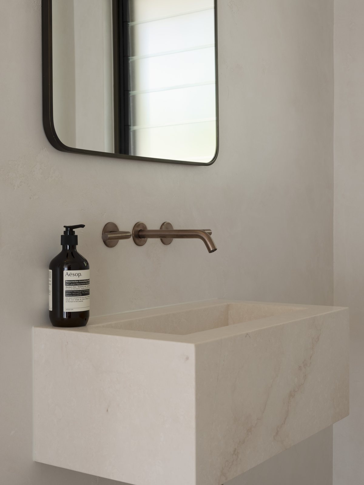 Wall-hung stone basin with a brushed bronze mixer in a Gold Coast powder room renovation