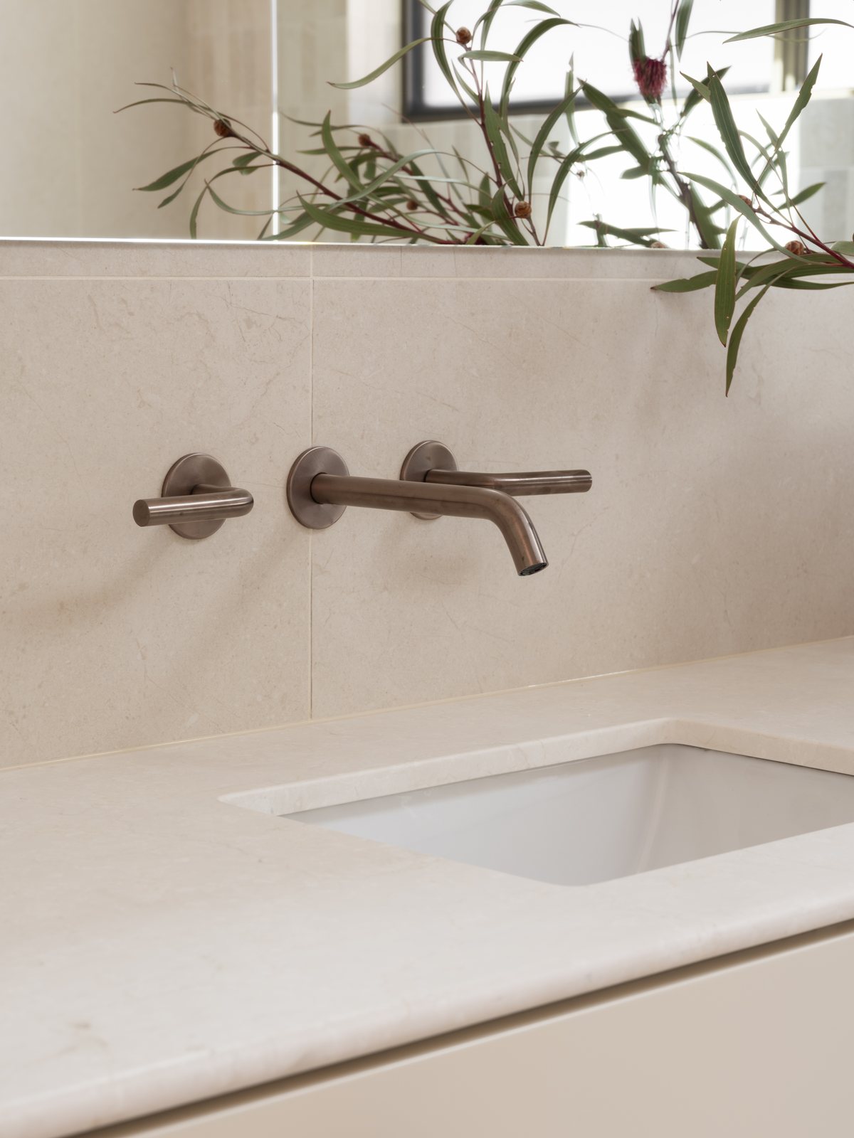 Brushed bronze mixer over a stone vanity with an undermount basin in a Gold Coast bathroom renovation