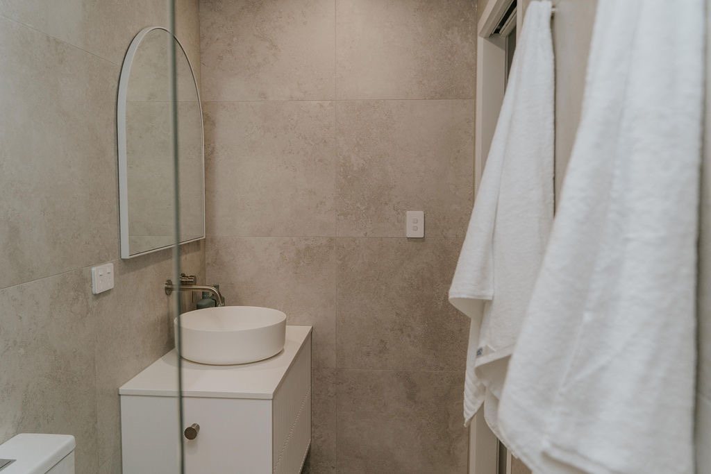 Vanity with a round mirror and timber towel rail in a Gold Coast bathroom renovation