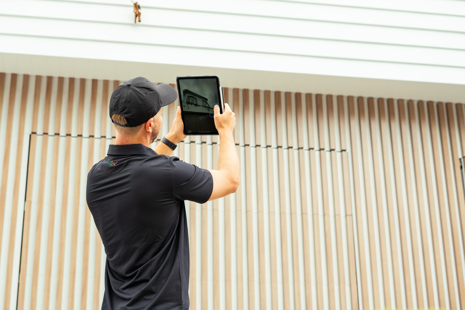 A CYTE inspector photographing external cladding on a Gold Coast property during a building inspection, recording a finding for the written report